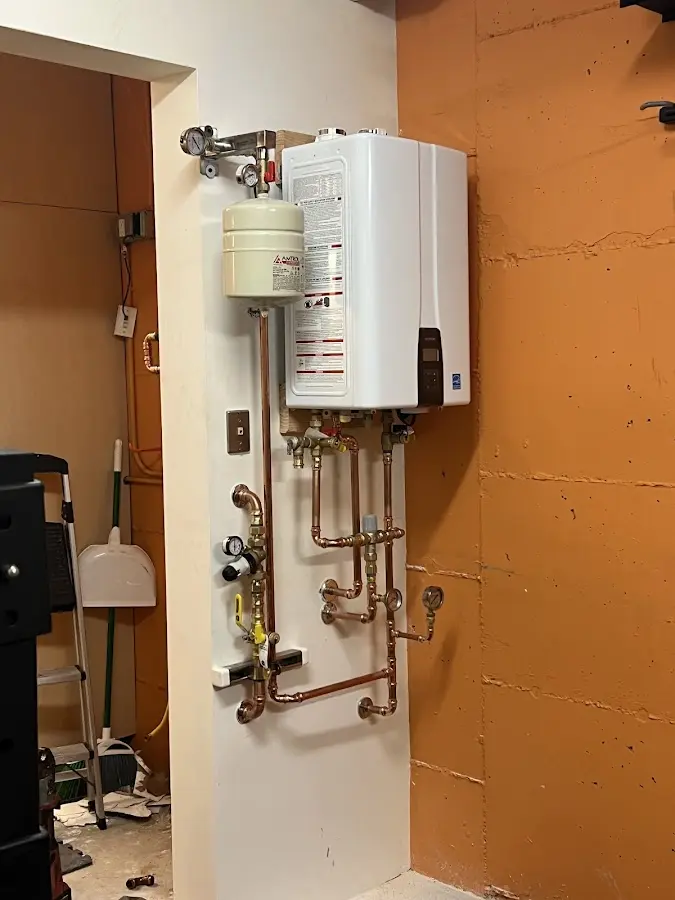 Plumbing technician inspecting water heater connections in Macedon